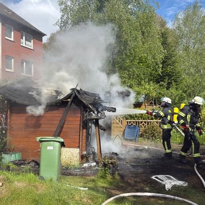 FW-AUR: Holzschuppen vor Wohngebäude in Vollbrand