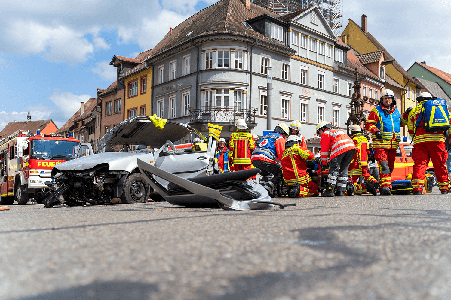 Ein Verkehrsunfall hat sich auf einer stark befahrenen Hauptkreuzung ereignet. Ein PKW ist stark beschädigt und steht mitten auf der Straße. Die Feuerwehr und der Rettungsdienst arbeiten Hand in Hand, um die Unfallstelle zu sichern und den Verletzten zu helfen.